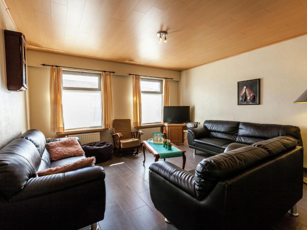 ein Wohnzimmer mit Ledersofas und einem TV in der Unterkunft In a quiet location nearby the woods in Ruiselede