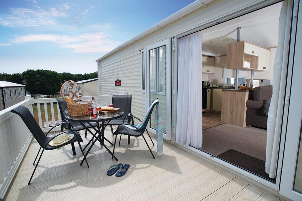 a patio with a table and chairs on a balcony at 7. Supreme OD 3 Caravan with Decking in Ringwood