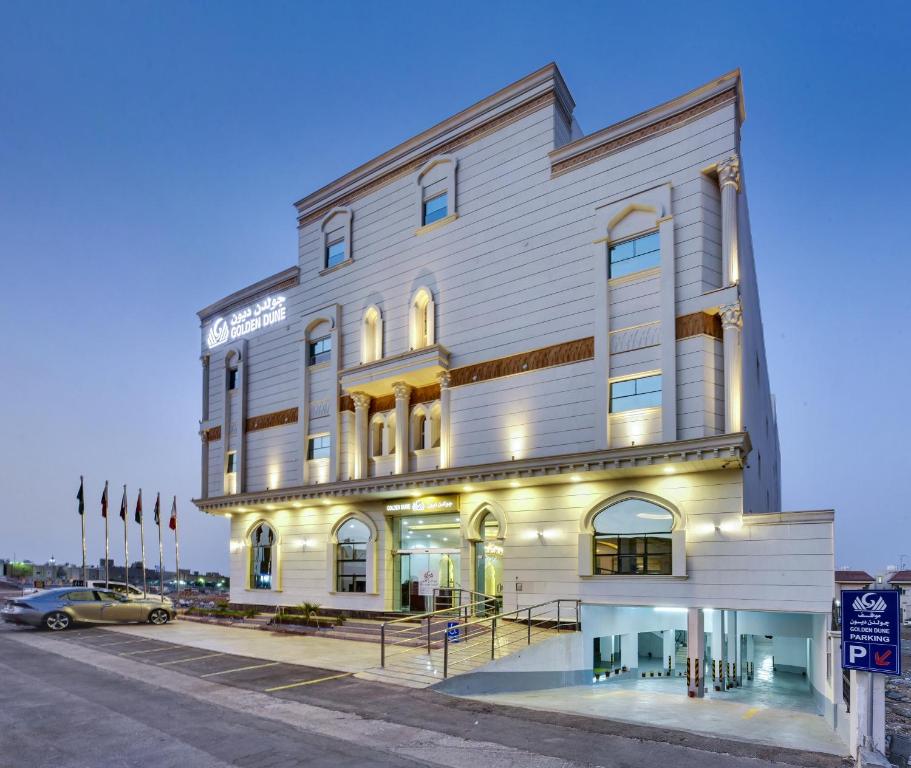 Golden Dune Hotel AlFayhaa في الرياض: مبنى أبيض كبير مع سيارة متوقفة أمامه