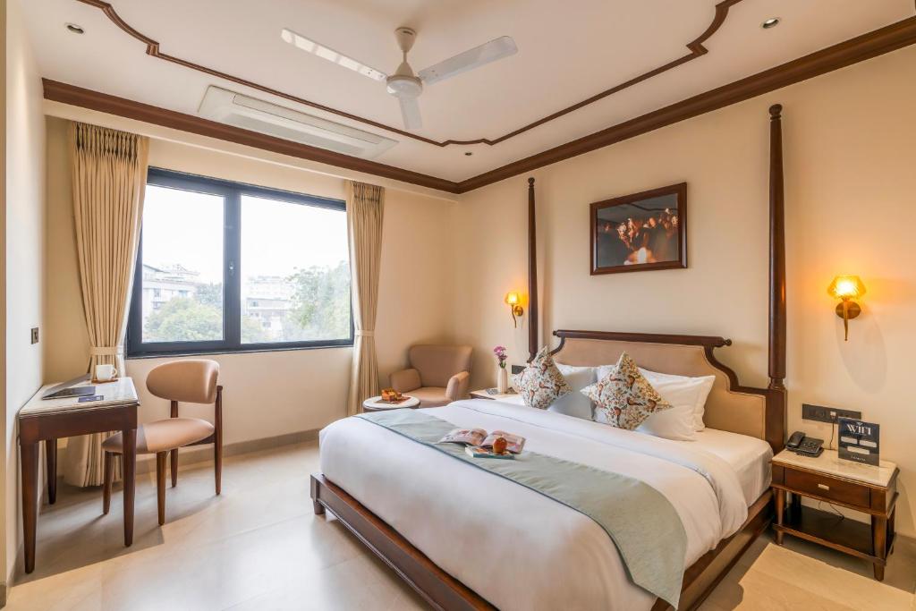 a hotel room with a large bed and a desk at Luxuria Varanasi By Moustache in Varanasi