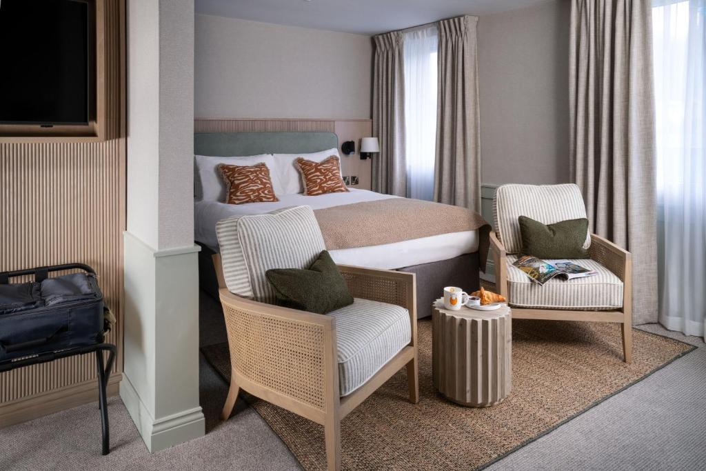 a hotel room with a bed and two chairs at North Lakes Hotel and Spa in Penrith