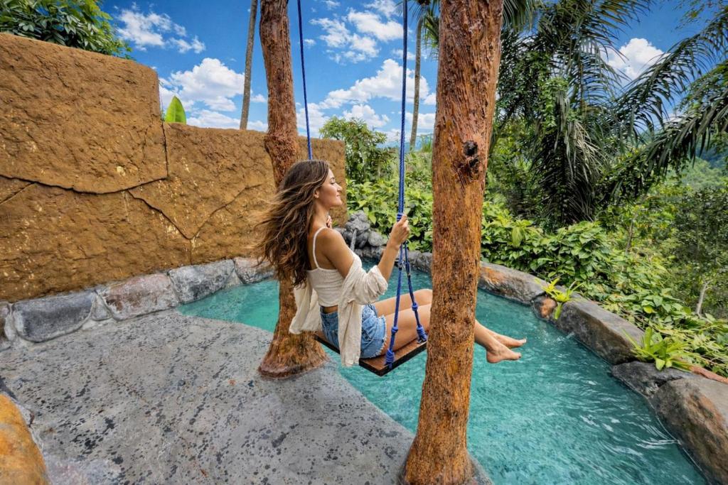 a woman on a swing in the water at a resort at Vana Nugraha Villas in Tampaksiring
