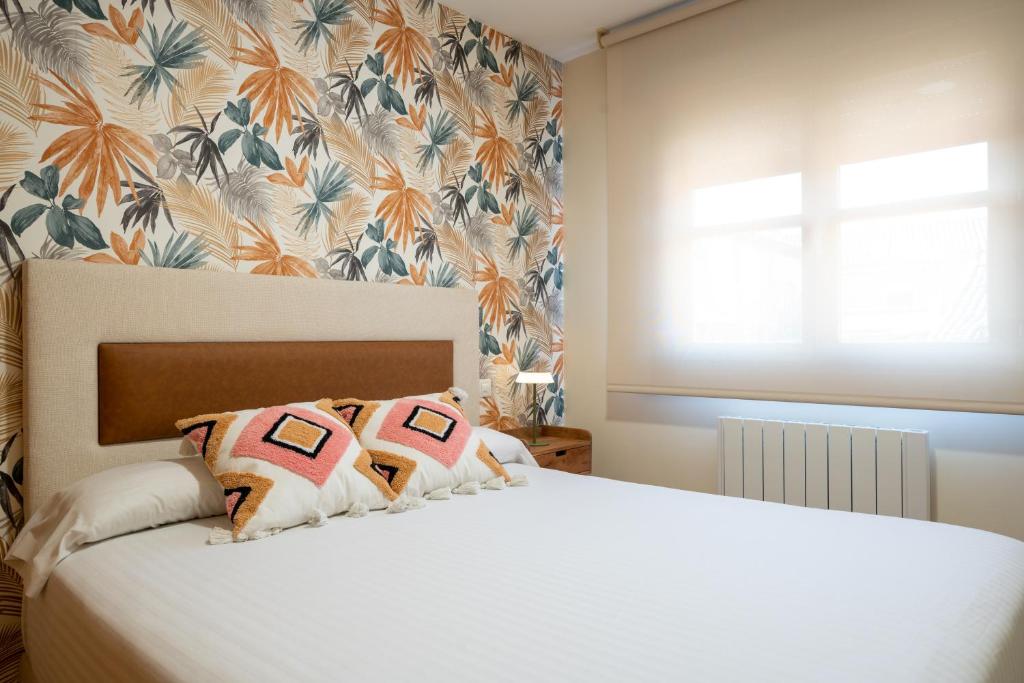 a bedroom with a white bed with a floral wallpaper at Apartamentos GO - Simancas in Simancas