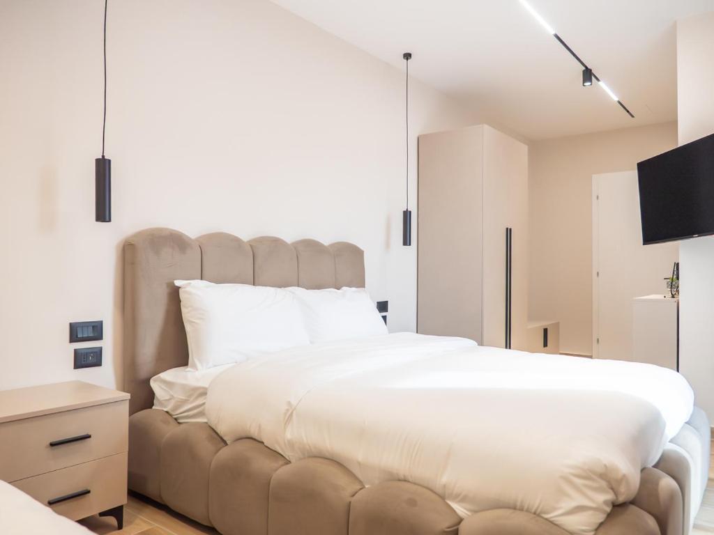 a bedroom with a large white bed and a tv at Enigma Rooms in Lezhë