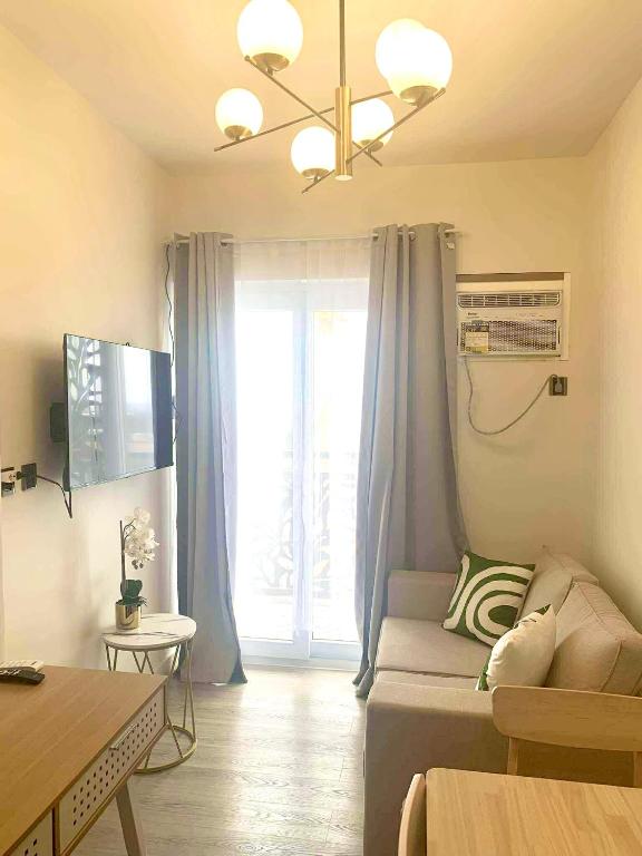 a living room with a couch and a large window at Cozy 1BR with Balcony, Sea View and Pool - Fast WiFi - Snug Sanctuary in Talisay