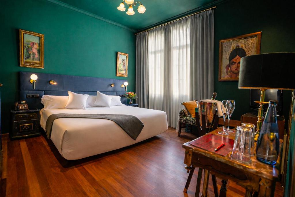 a bedroom with a large bed and a green wall at Casa Inquieta Hotel Boutique in Seville