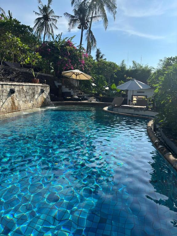 a swimming pool with blue water in a resort at Lombok Coconut Hotel in Mangsit