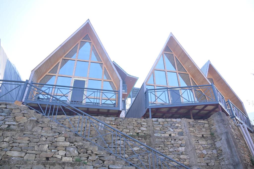 a house on top of a stone wall at Alpine Vista Wellness & Resort in Gupta Kāshi