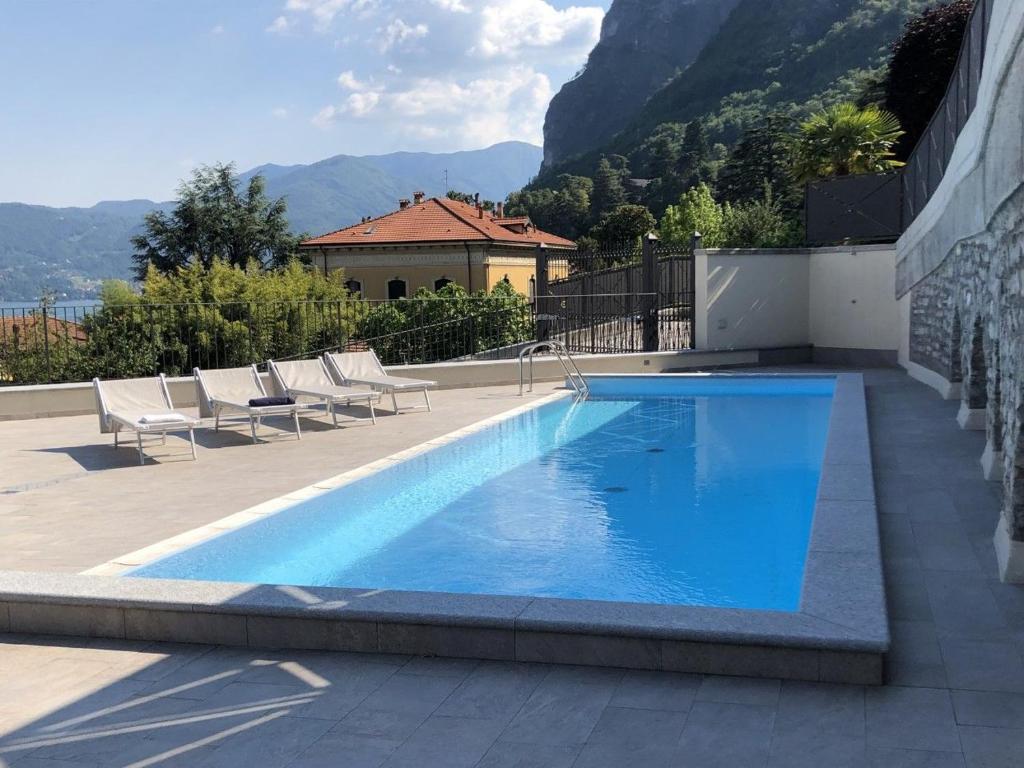 a blue swimming pool with chairs and a building at Casa Julia - Menaggio by LoveComo in Menaggio