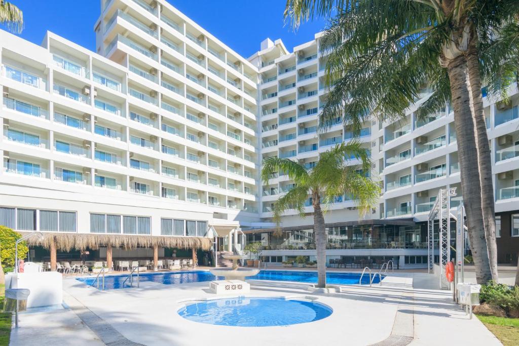 an apartment building with a pool and palm trees at Hotel Parasol by Dorobe in Torremolinos
