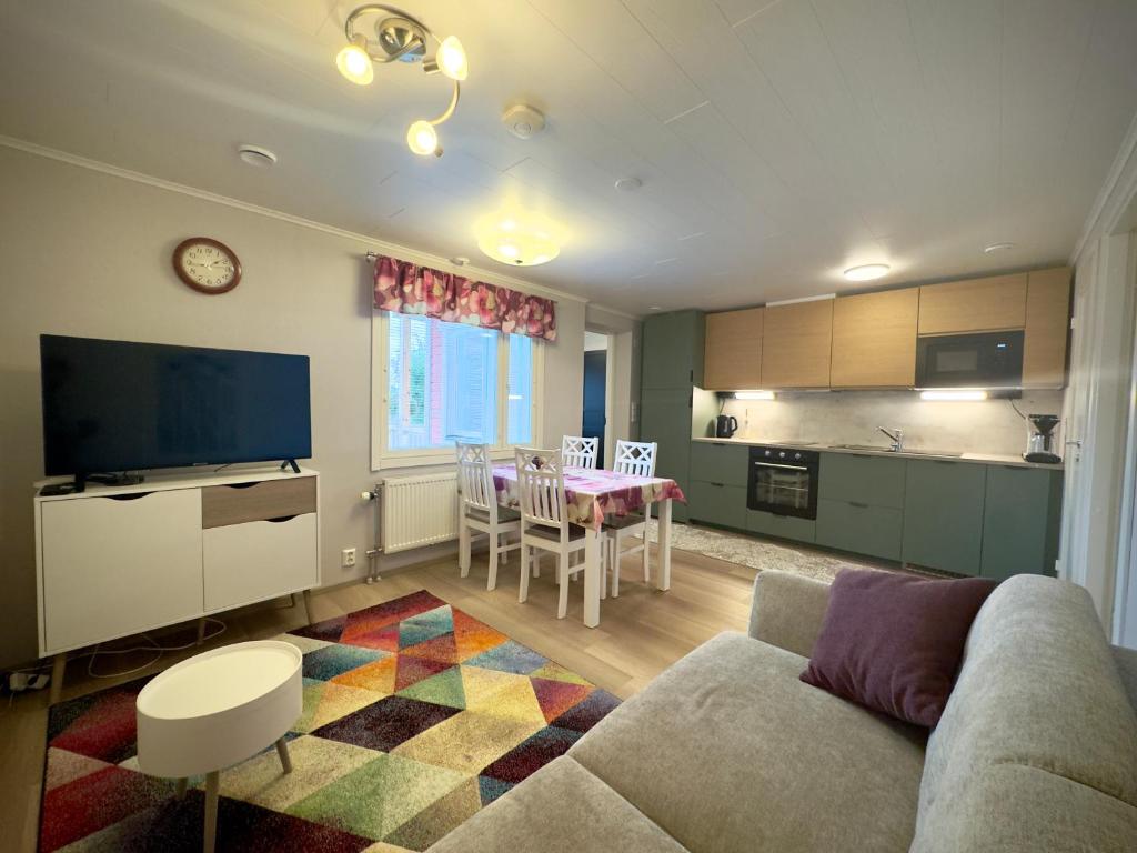 a living room with a couch and a kitchen with a table at Riihen Tupa in Äkäslompolo