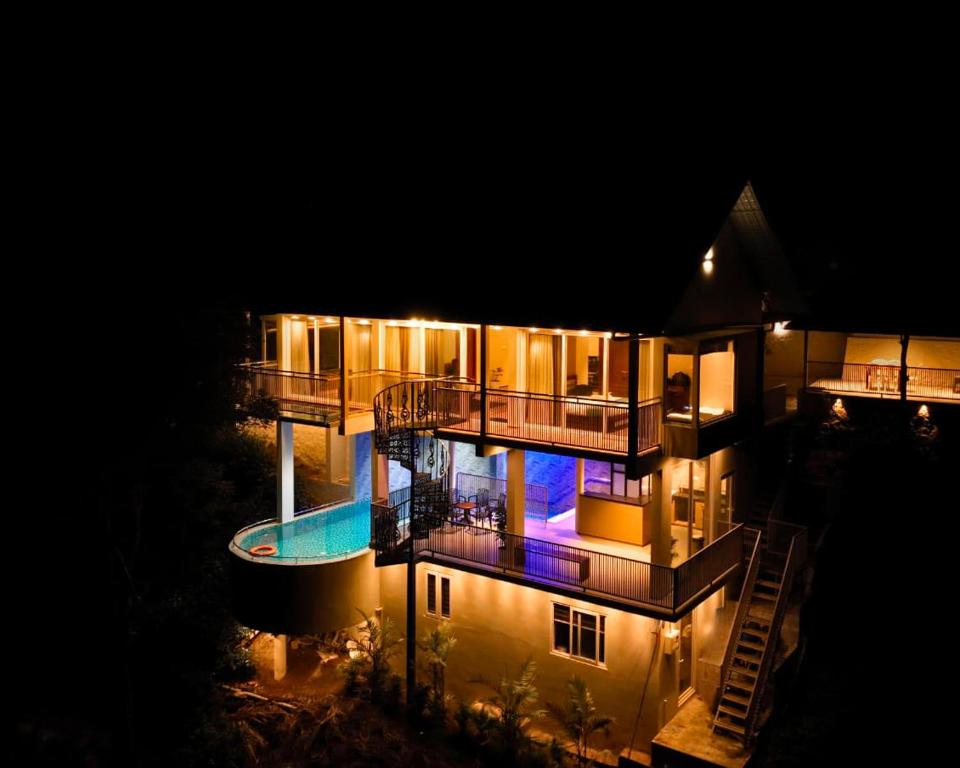 a large building with a swimming pool at night at La Paraiso by WhiteTrip in Vagamon