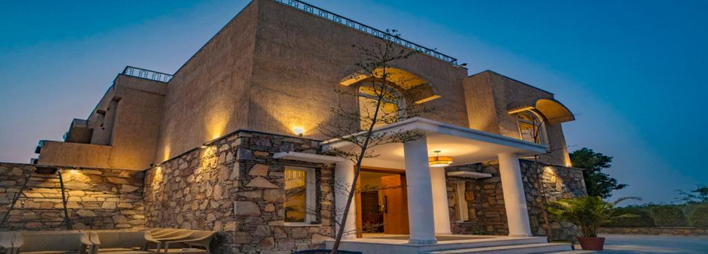 a large stone building with a tree in front of it at Maanya by the Lake By Samav hotels in Udaipur