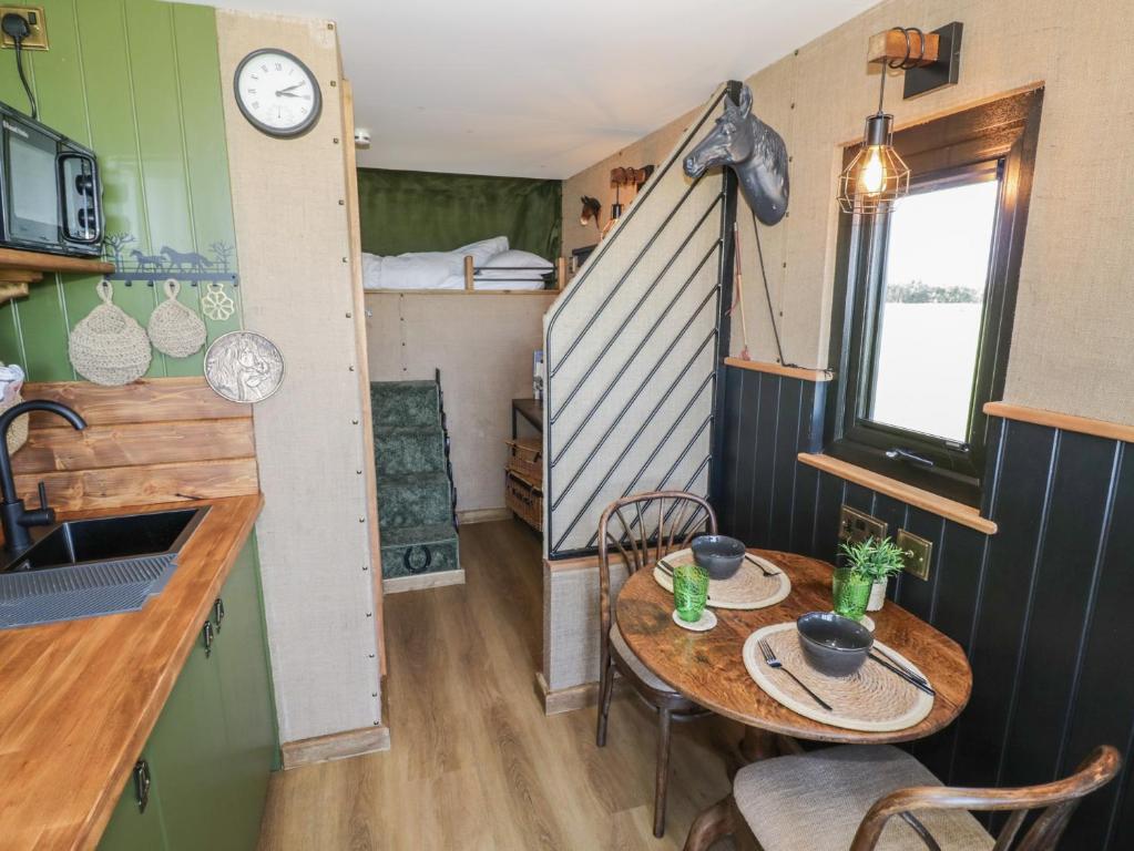 a tiny house with a table and a room with a bed at GiGi's Horsebox in Evesham