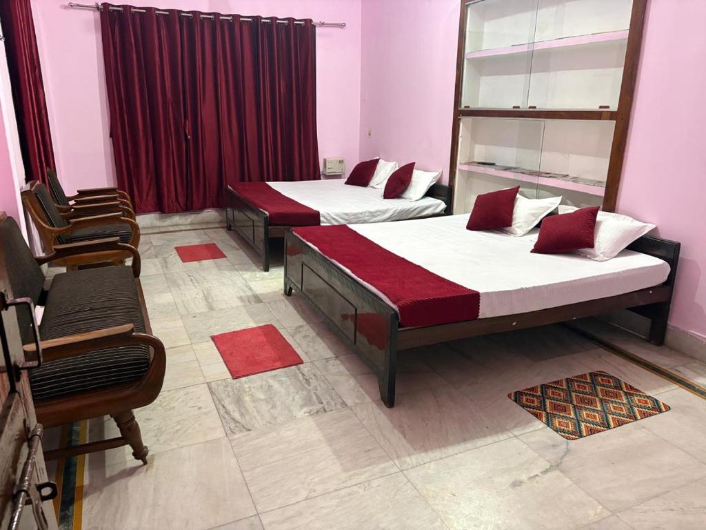 two beds in a room with red curtains at Hotel Padamaa Palace in Varanasi