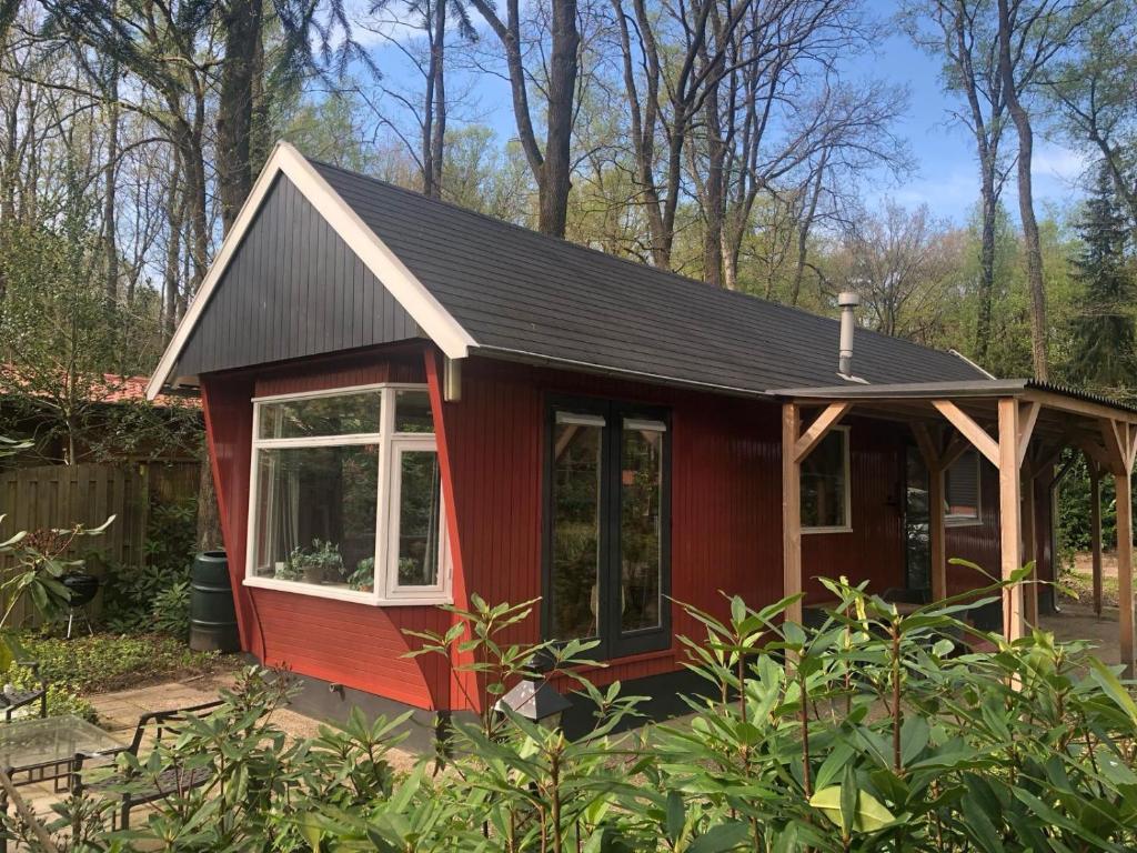 a red tiny house with a black roof at Huisje bij de Bronnen in Nutter