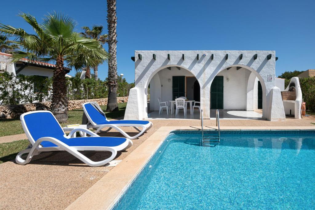a pool with two lounge chairs and a house at Villa Flor by 3VILLAS in Cala en Bosc