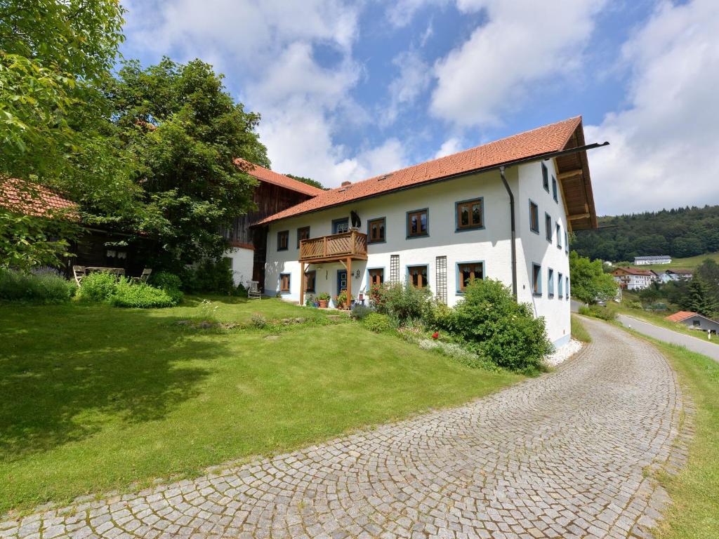 uma grande casa branca com uma estrada de cascalho em frente em Former farmhouse with sunbathing lawn em Zenting