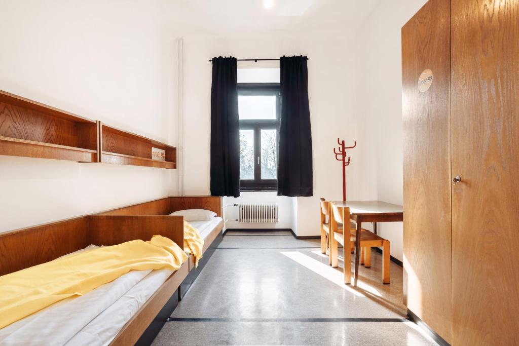 a room with two beds and a table and a dining room at NUMBR25 - self service & low budget Hotel in Graz