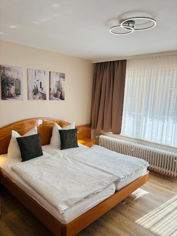 a bedroom with a bed with white sheets and a window at Hotel Europa Pforzheim in Pforzheim