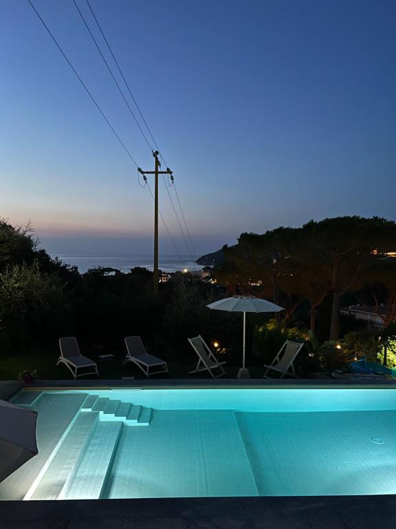 a swimming pool with chairs and an umbrella at Pisolo in Procchio