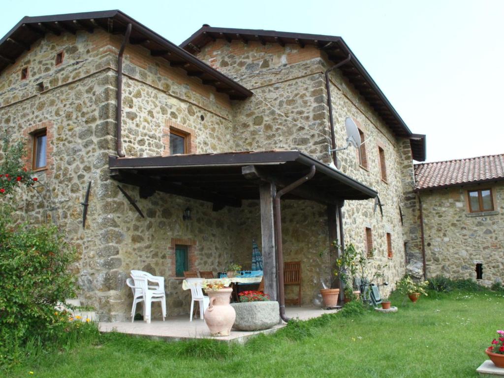 uma casa de pedra com uma mesa e cadeiras em frente em Alluring Holiday Home in Canossa with Pool Garden Barbecue em Mulazzo
