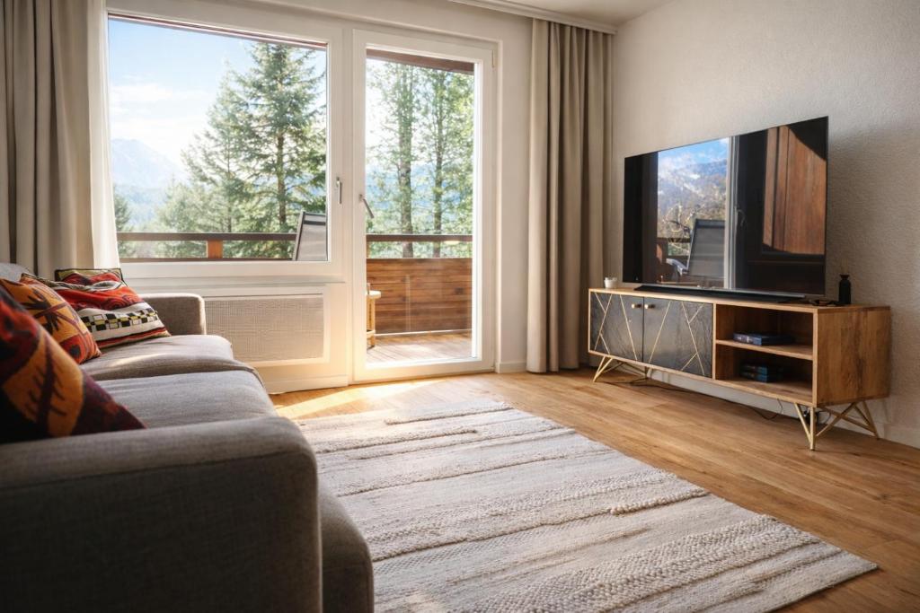 a living room with a couch and a flat screen tv at Chalet Höfi - Ski-in Ski out at Hörnlilift by Arosa Stay in Arosa