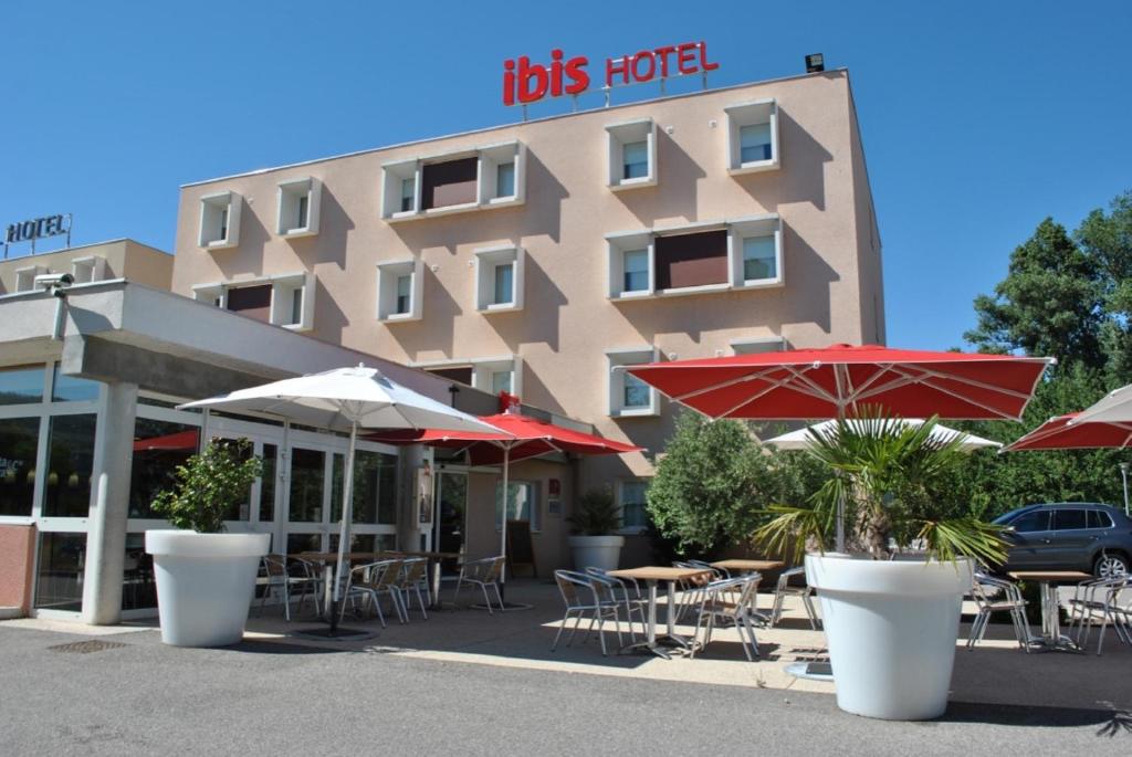 ein Hotel mit Tischen und Sonnenschirmen davor in der Unterkunft ibis Loriol Le Pouzin in Le Pouzin