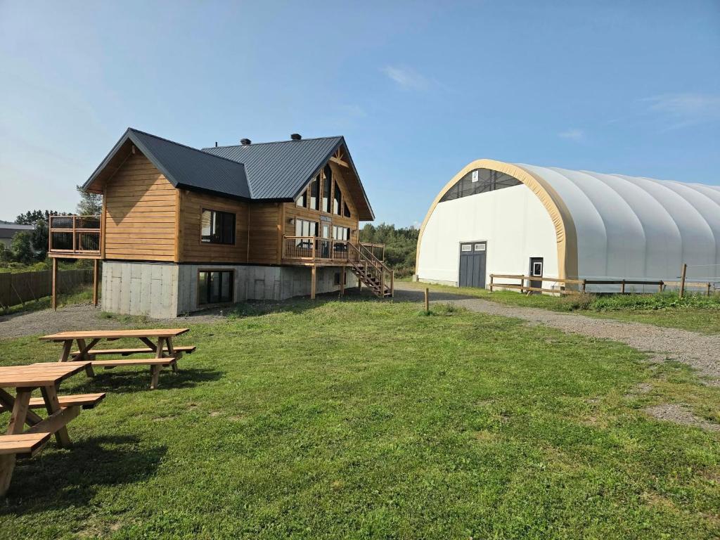 a barn and picnic tables in a field with a building at #1 Le refuge et #2 Le Gite in Saint-Onésime