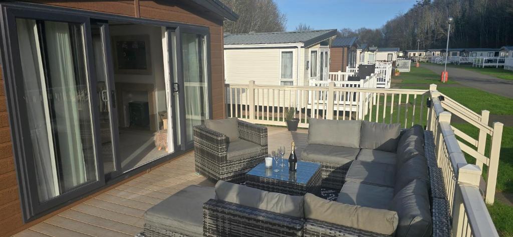 a deck with a couch and chairs on a porch at Thurston Manor Holiday Park - Woodlands 1 in Innerwick