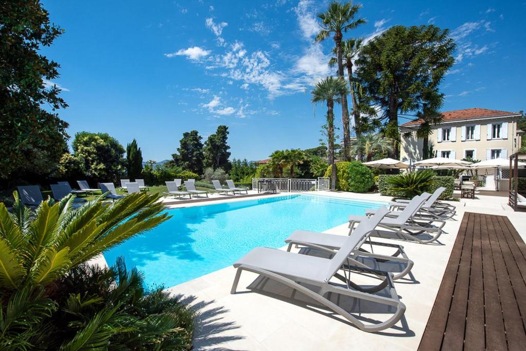 a pool with white lounge chairs next to a building at Hôtel Château de la Tour Cannes in Cannes