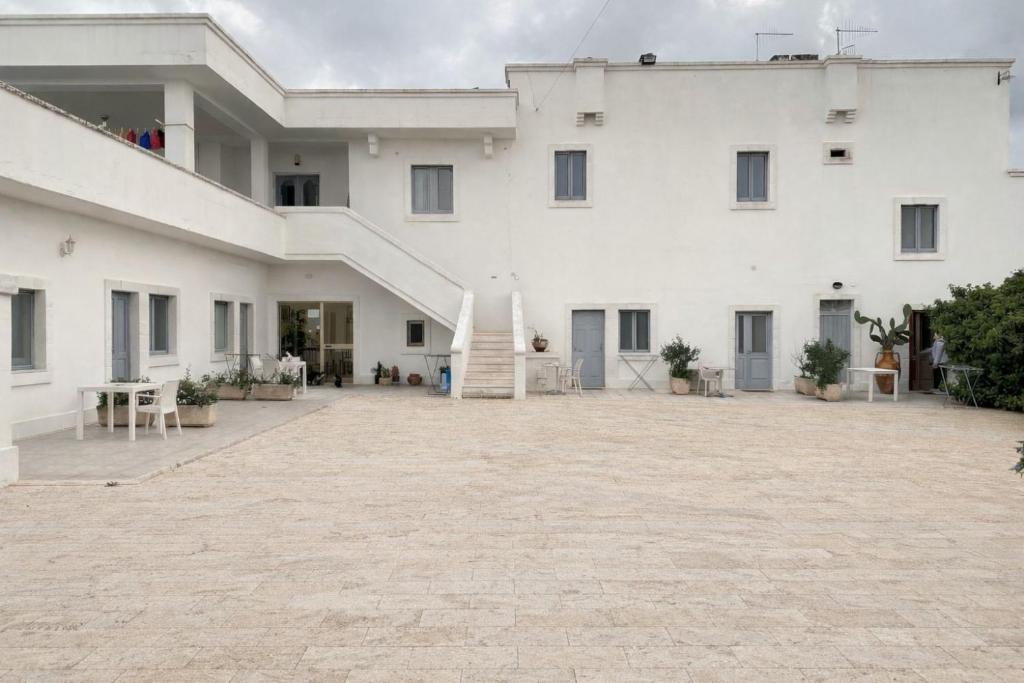 a large white building with a staircase in a courtyard at Masseria Lama D'impisa in Fasano