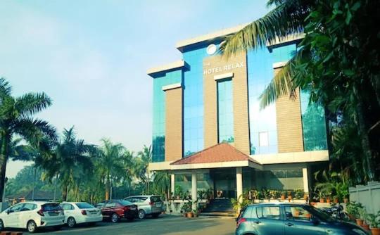 a large building with cars parked in front of it at The Hotel Relax in Kankauli
