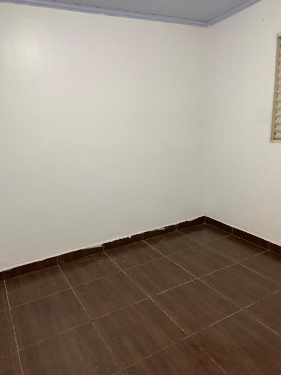 a room with a white wall and a wooden floor at Casa para MotoGP in Goiânia