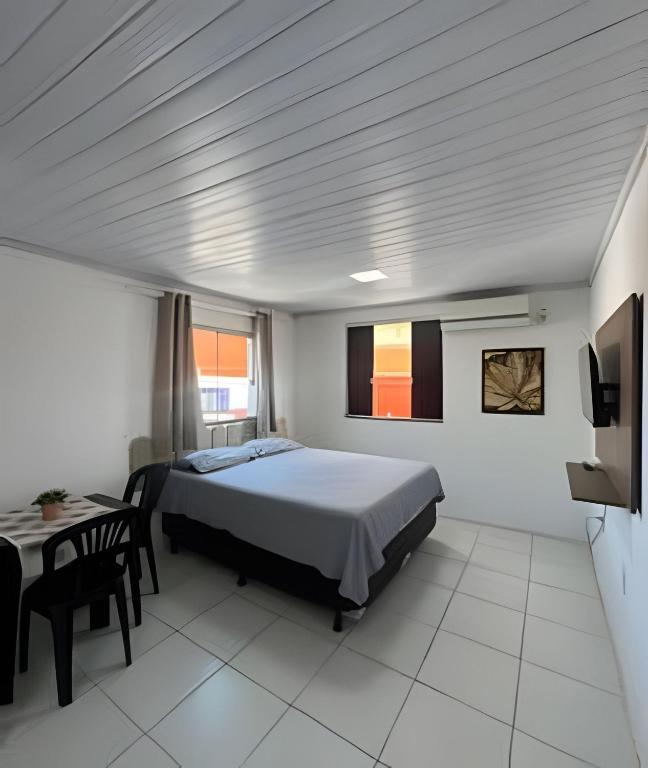 a bedroom with a bed and a table and a tv at Studio luxo Periperi in Salvador
