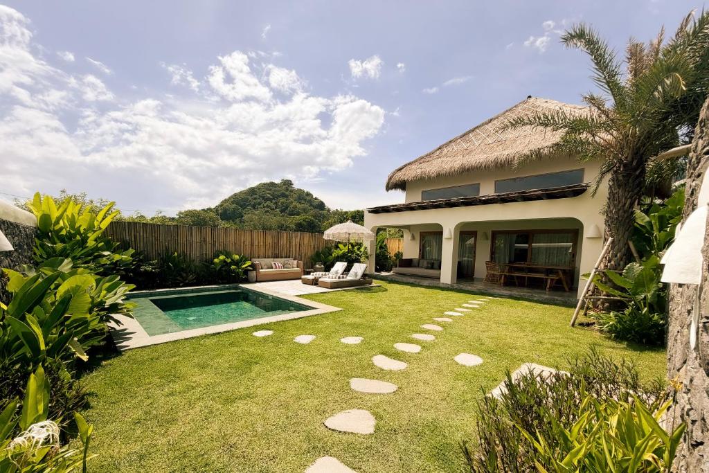 a backyard with a swimming pool and a house at Irama Surf Villas - Private Pool Villas at Yoyos in Sekongkang