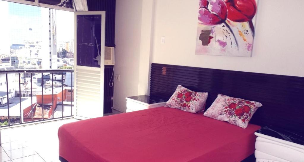 a bedroom with a bed with red sheets and pillows at Suíte panorama histórico in Manaus
