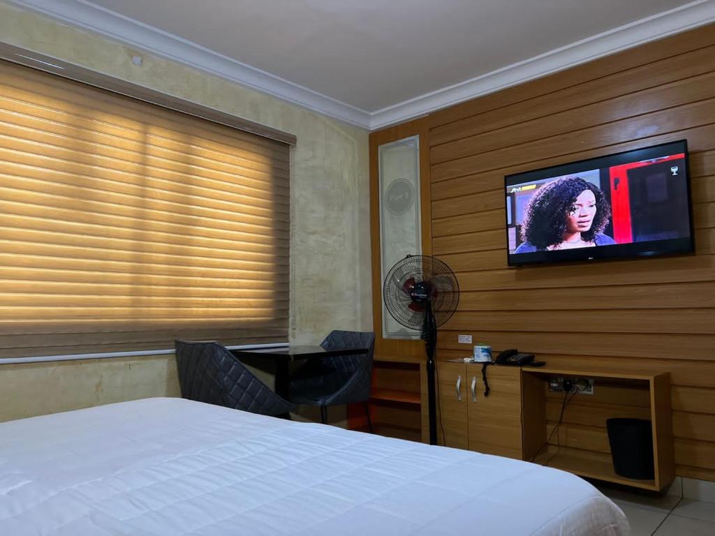 ein Schlafzimmer mit Bett und Flachbildfernseher in der Unterkunft Plot1 Suits in Ibadan