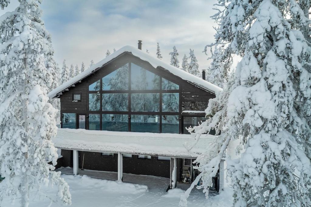 a log cabin in the snow with snow covered trees at ConstaVilla by Hilla Villas in Kolari
