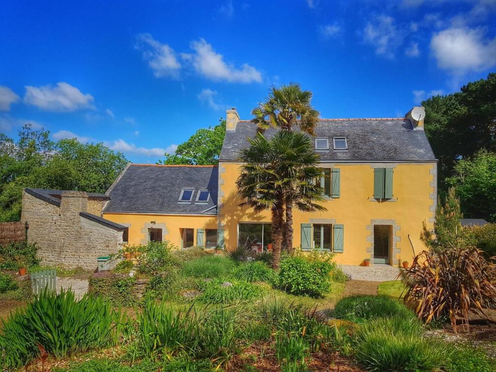 a yellow house with a palm tree in the yard at La maison jaune - 3ch - 6pers in Loctudy