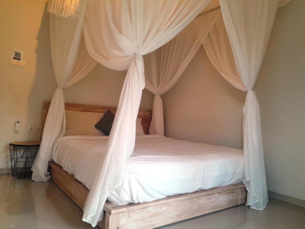 a bedroom with a canopy bed with white drapes at Maha Rama Villas Amed in Amed