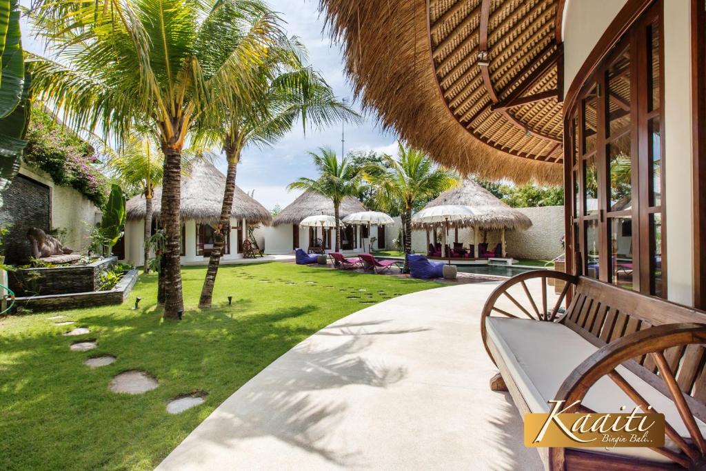a porch of a resort with a bench and palm trees at Villa Kaaiti in Uluwatu