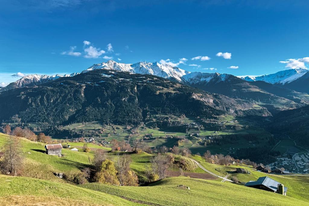 a green hill with mountains in the background at Gemütliche Ferienwohnung in Ladir bei Flims Laax in Ilanz