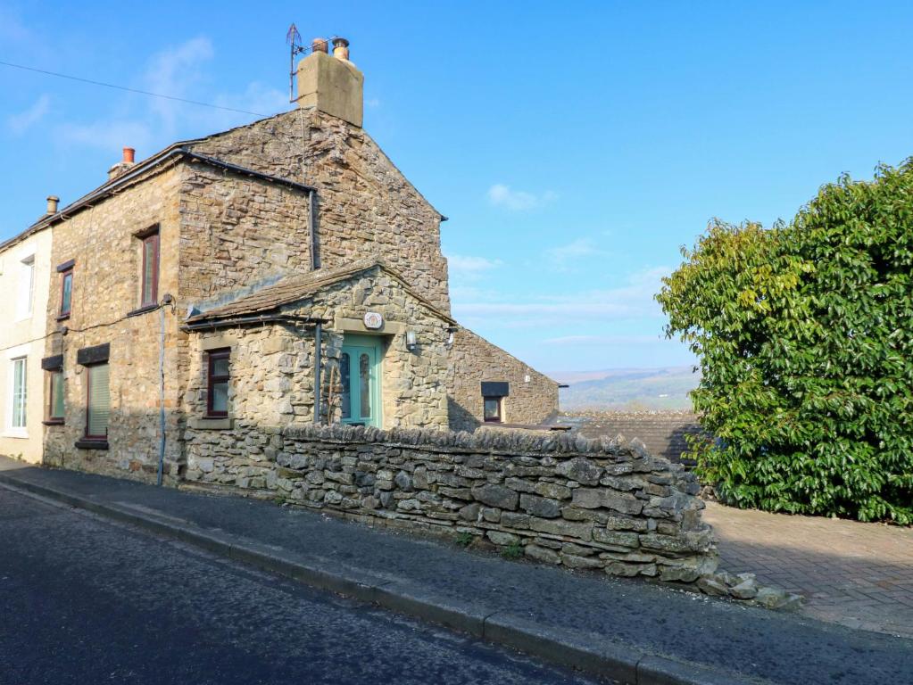 an old stone building on the side of a road at Eastend Cottage in Leyburn