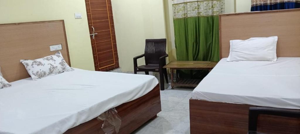 two beds in a room with a chair and a desk at Varanasi Paying Guest House Assi Ghat in Varanasi