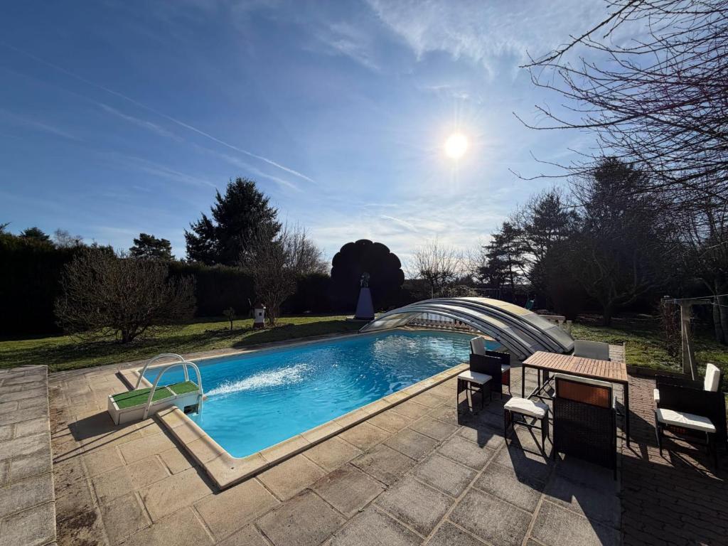 a swimming pool with a table and chairs next to it at La fleur des eaux de Beauval in Noyers-sur-Cher