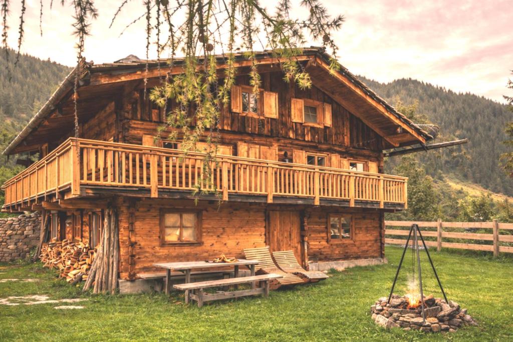 a log cabin with a deck and a picnic table at Almhütte Santnerhof - Hochgebirgshütte 1750m - This is a remote high mountain hut in Virgen