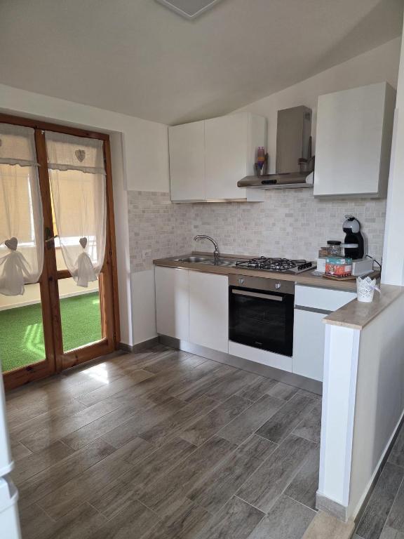 a kitchen with white cabinets and a stove top oven at Ampia terrazza privata a due passi da Pizzo e Tropea in Vibo Valentia Marina