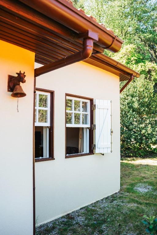 a small white house with a brown roof and two windows at Casa da Avó Lina by Quantique in Vieira do Minho