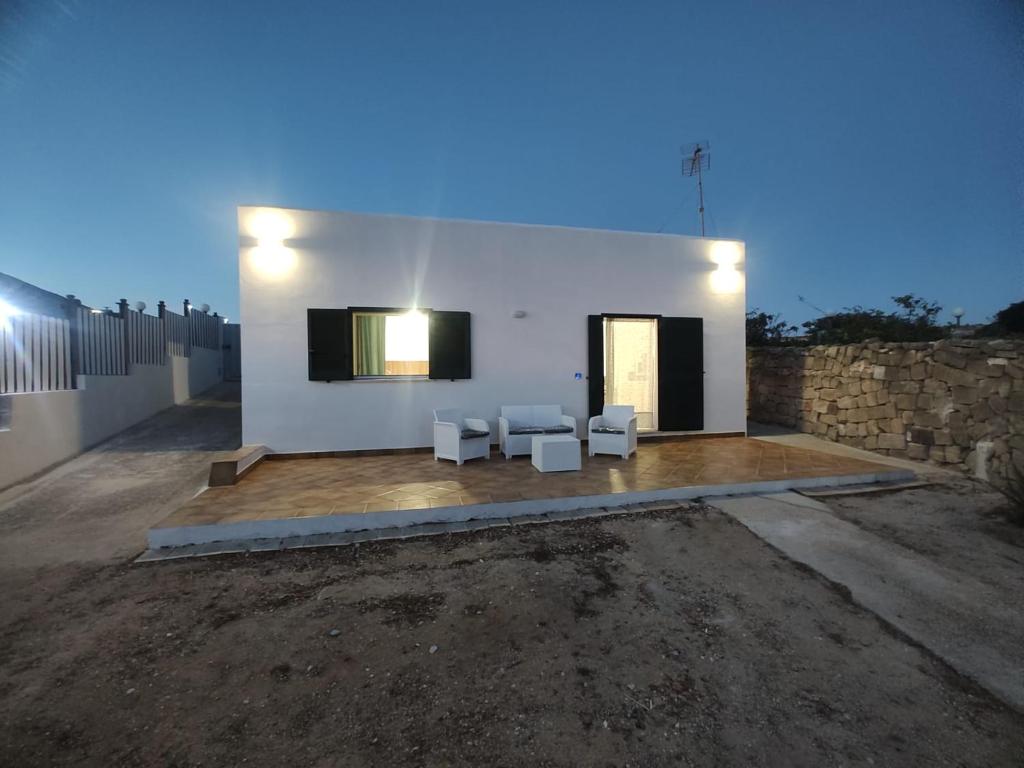 a white building with two white chairs and a wall at villa ingrassia in Favignana